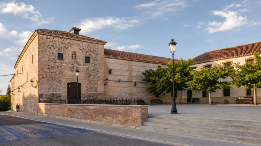 Recreación editorial de la fachada de piedra y ladrillo de un convento con la plaza vacía delante