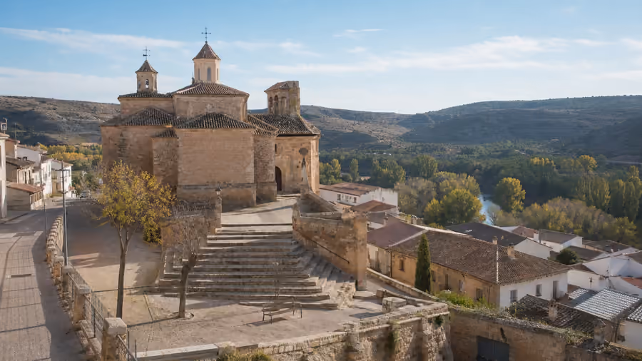 Recreación editorial de una iglesia de piedra sobre una escalinata, con el valle del río al fondo