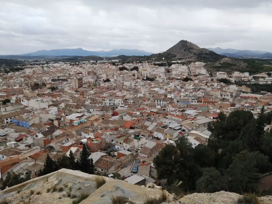 Panorámica real del casco de Calasparra desde el castillo, con tejados, cerros y montañas bajo un cielo nublado