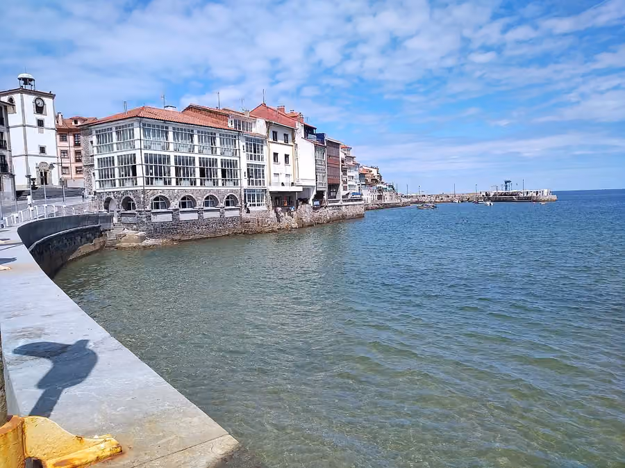 Fachada marítima de La Ribera de Luanco, con la Torre del Reloj, casas y el antiguo muelle