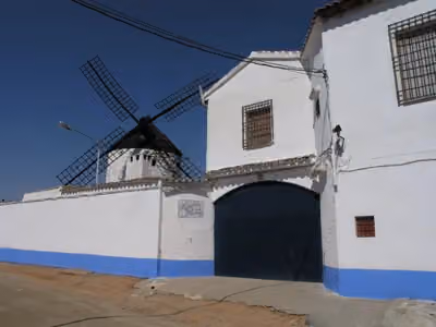 Entrada blanca y azul del recinto del molino del Tío Genaro, con sus aspas al fondo