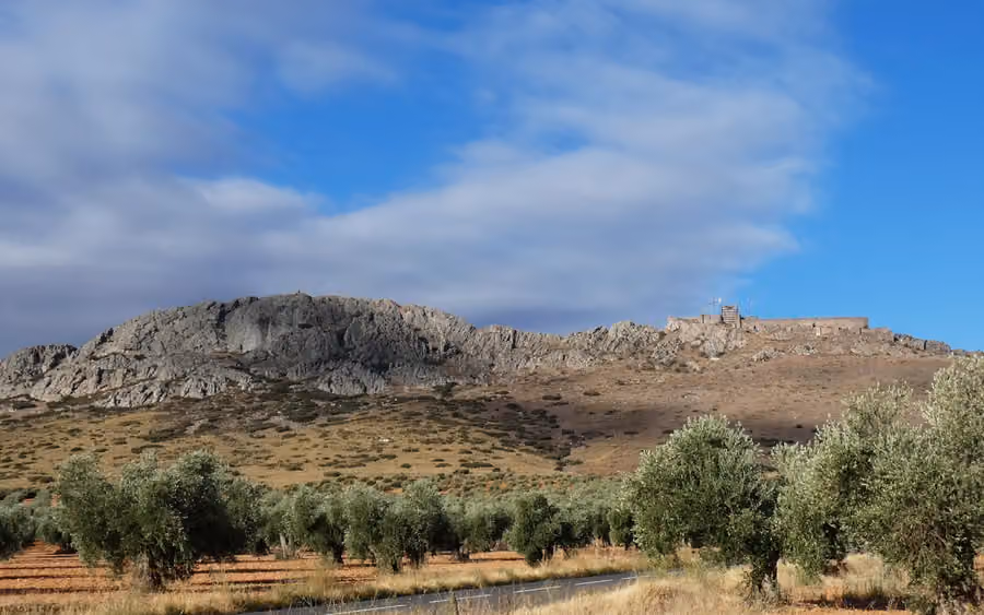 Castillo de Peñas Negras de Mora sobre la sierra, con olivares en primer plano
